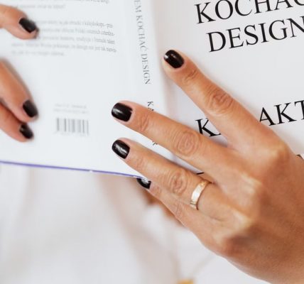 Unrecognizable female reading book while sitting at home during free time and relaxing during weekend