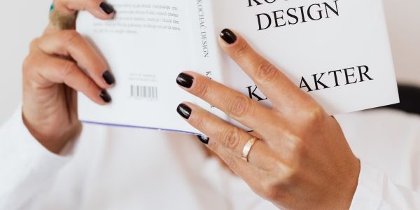 Unrecognizable female reading book while sitting at home during free time and relaxing during weekend