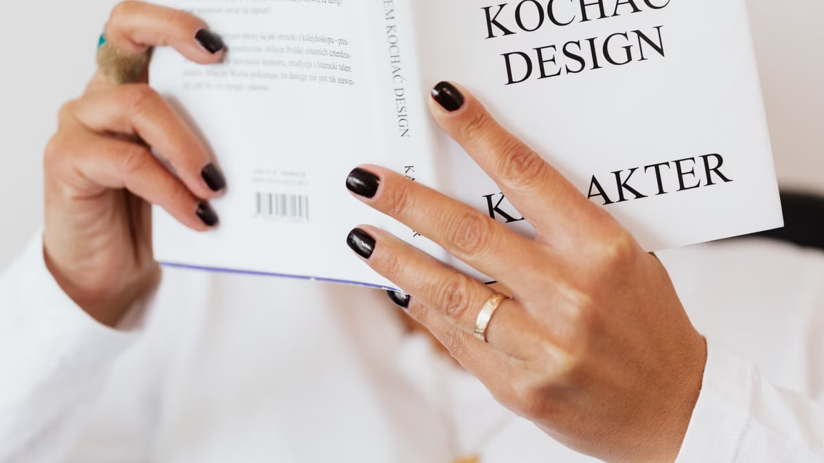Unrecognizable female reading book while sitting at home during free time and relaxing during weekend