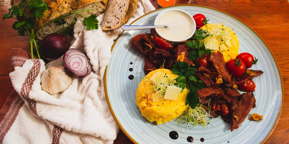 Delicious Romanian cuisine featuring polenta, vegetables, and artisan bread in a vibrant setting.
