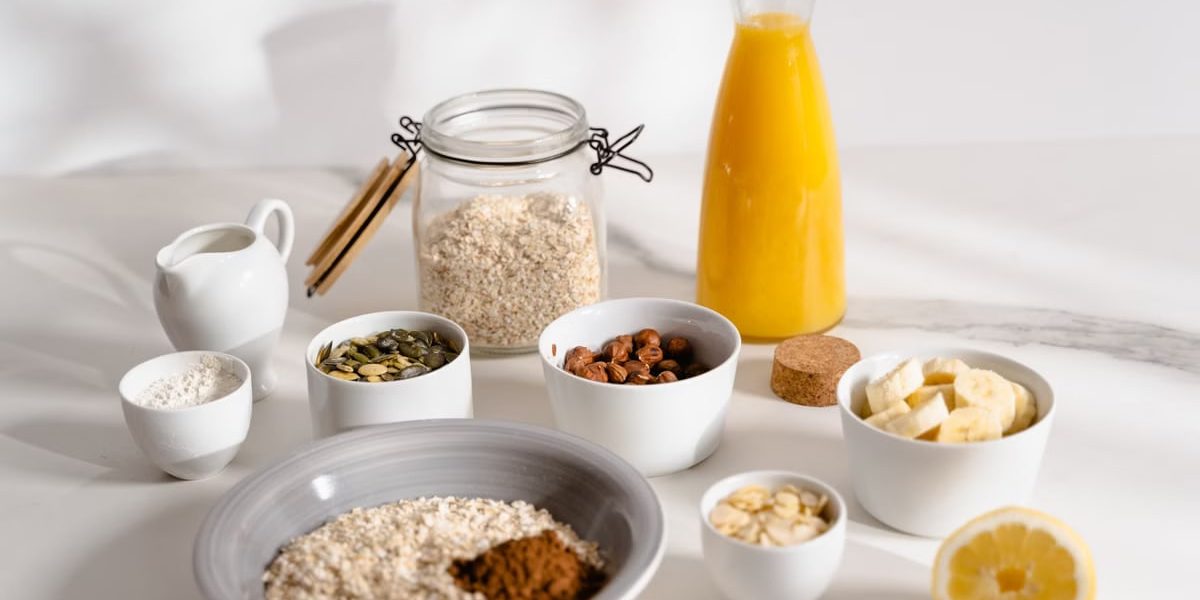 Delicious breakfast ingredients featuring oats, nuts, and fresh orange juice on a bright surface.