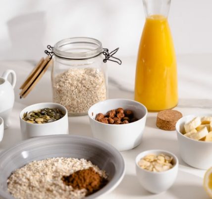 Delicious breakfast ingredients featuring oats, nuts, and fresh orange juice on a bright surface.