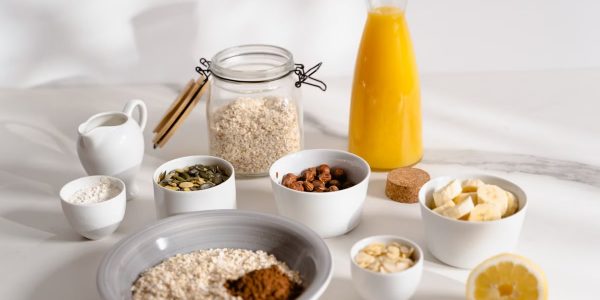 Delicious breakfast ingredients featuring oats, nuts, and fresh orange juice on a bright surface.