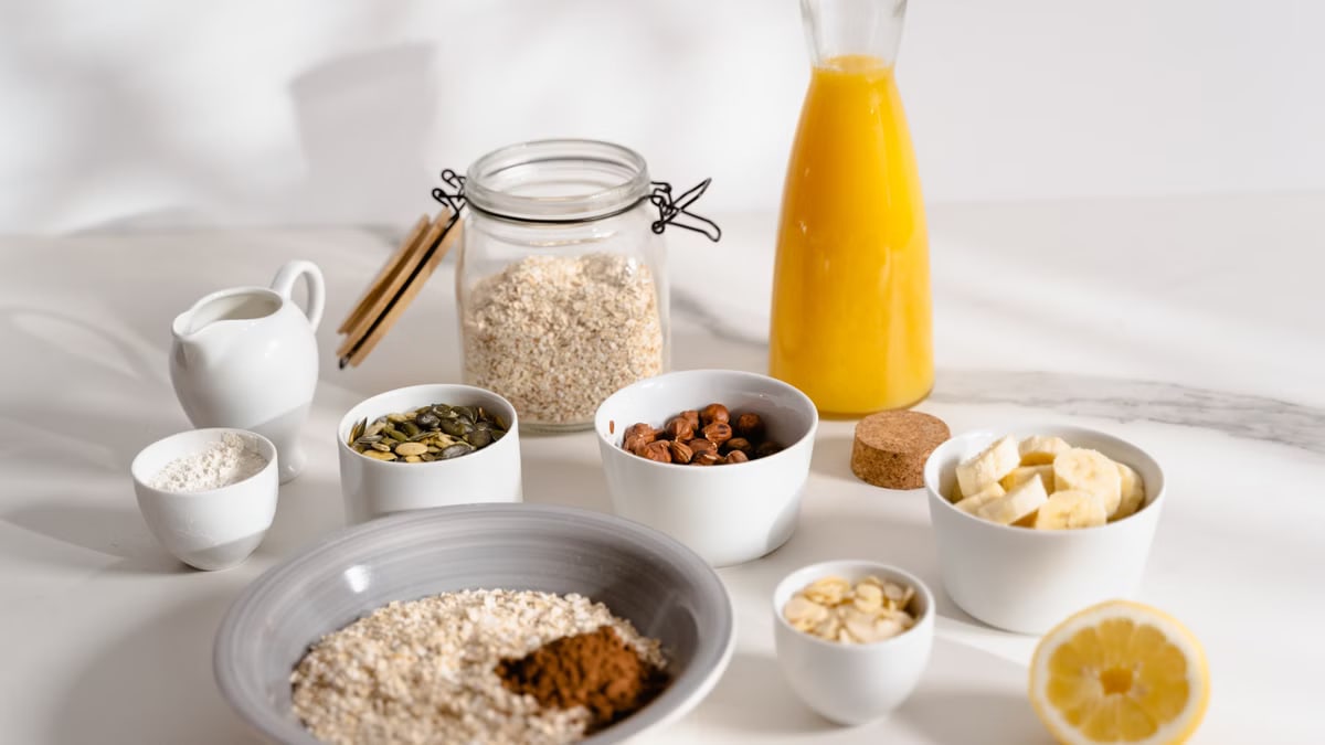 Delicious breakfast ingredients featuring oats, nuts, and fresh orange juice on a bright surface.