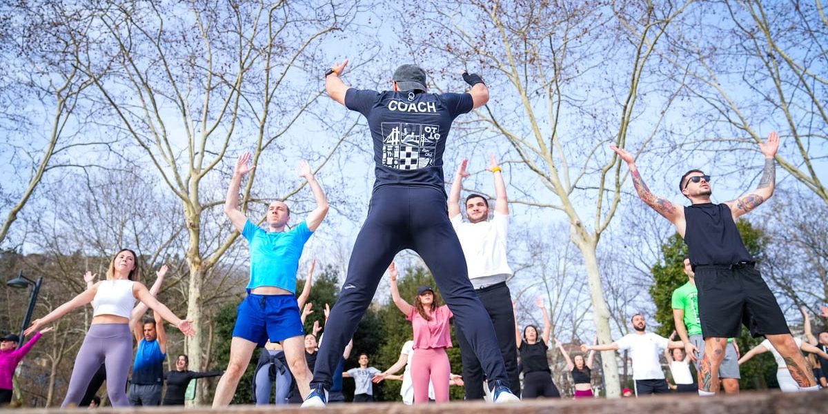 Group exercise session in a sunny Istanbul park led by a fitness coach outdoors.